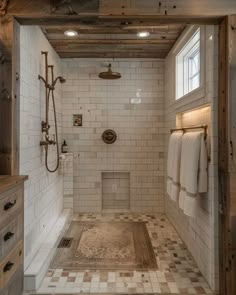 a bathroom with white tile and wood accents on the walls, along with an open shower