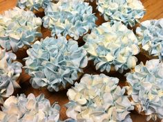 blue and white cupcakes with frosting flowers on them sitting on a table