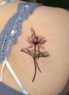 the back of a woman's shoulder with a flower tattoo on her left side