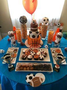 a blue table topped with lots of food and desserts covered in sports themed decorations