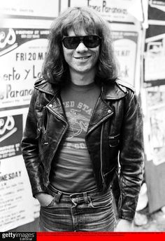 a man with long hair and sunglasses standing in front of signs