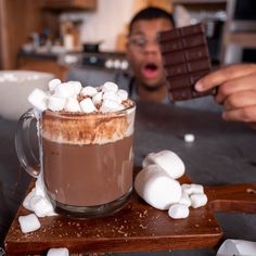 a person holding up a chocolate bar with marshmallows on it in front of them