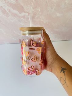 a hand holding a small jar with hearts on it and a string attached to the lid