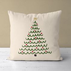 a white pillow with a green christmas tree on the front and red berries on the back