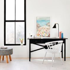 a white room with black windows and a desk in the corner next to a chair