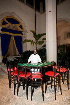 a man sitting at a table with red chairs