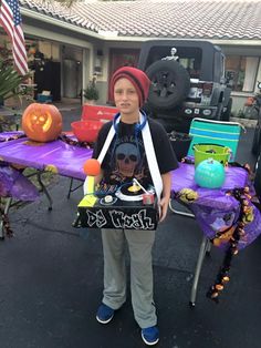 a young boy standing in front of a purple table with decorations on it and an american flag