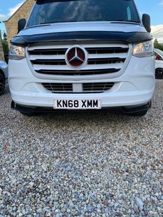 the front end of a white van parked on gravel