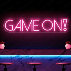 a neon sign that says game on above three stools