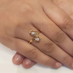 a woman's hand wearing a gold ring with two diamonds on the middle finger