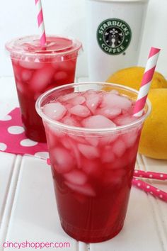 two cups filled with ice next to lemons and a cup of starbucks coffee on a table