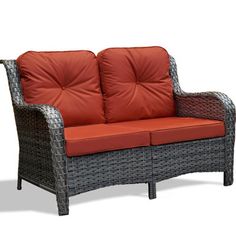 a wicker couch with an orange cushion on it's back and armrests