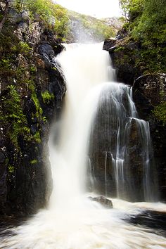 there is a waterfall that has water coming out of the rocks and into the river