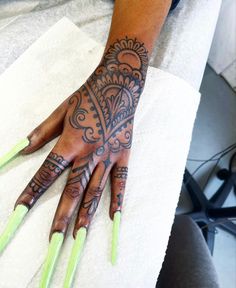 a woman's hand with tattoos on it and green nails in front of her