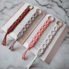 three crocheted tassels are on top of an open book, one is pink and the other is white