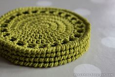 two crocheted coasters sitting on top of each other in front of a polka dot tablecloth