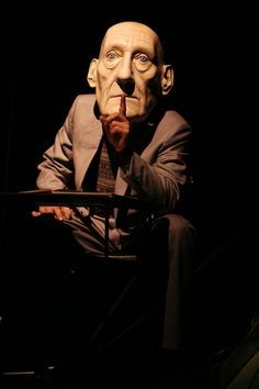 a man sitting in a chair with a creepy mask on his face