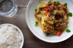 a white plate topped with food next to a bowl of rice