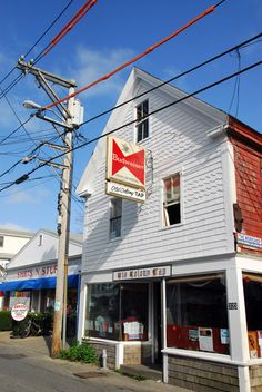 an old white building on the corner of a street with power lines in front of it