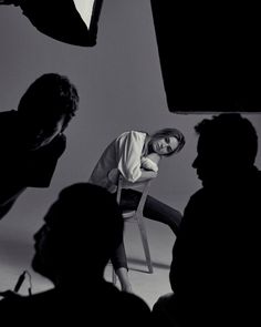 a black and white photo of a woman sitting on a chair in front of people