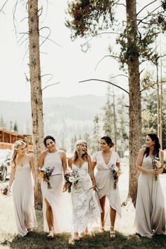 a group of women standing next to each other in front of some trees and grass