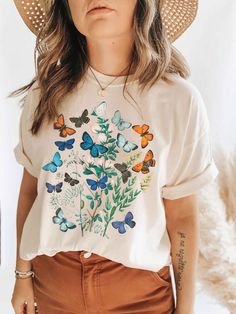 The Butterflies! Flowers! So gorgeous all together across this t-shirt with a vintage feel. The t-shirt is unisex sizing, made to be inclusive for both men and women. C O L O R S ✺ Natural I N K ✺ Eco-friendly, water-based M A T E R I A L ✺ 100% cotton ✺ Preshrunk ✺ Lightweight F I T + S I Z I N G ✺ UNISEX t-shirt ✺ Please review the size chart in the photos for measurements I M P O R T A N T ✺ Processing time to make your item is typically 1-7 business days. ✺ If you need to CANCEL or CHANGE yo Botanical Tshirt, Friendly Aesthetic, Luanna Perez, Alt Aesthetic, Indie Clothing, Butterfly T Shirt, Butterfly Shirt, Mori Kei, Butterflies Flowers