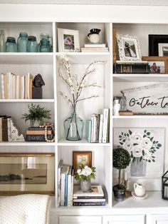 a white bookcase filled with lots of books and vases on top of it