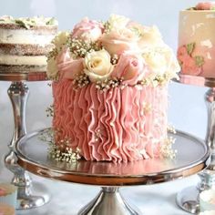 a pink cake with white flowers and baby's breath icing on a silver platter