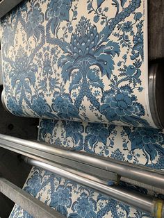 a blue and white floral wallpaper with metal piping