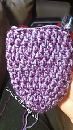 a crocheted pot holder is being held by someone's hand with a pair of scissors in it