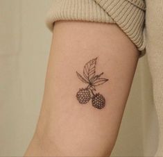 a woman's arm with a small tattoo of berries and leaves on the wrist