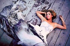 a woman laying on the ground next to a wooden fence with her hands behind her head