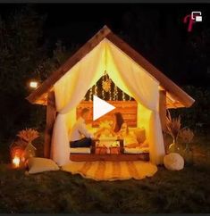 a couple is sitting in a small wooden house with lights on it's roof