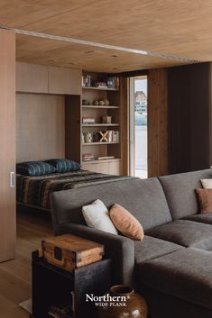 a living room filled with furniture next to a bed and book shelf on top of a hard wood floor