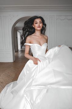 a woman in a white wedding dress is posing for the camera with her long black hair