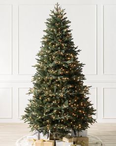 a small christmas tree with presents under it on a white plate and wood flooring