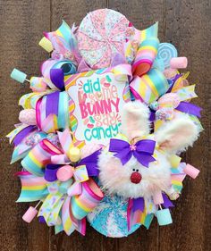 a colorful wreath with bunny ears and candy on the front is displayed against a wooden wall