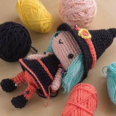 crocheted dolls and balls of yarn sitting on a table with one doll wearing a witches hat