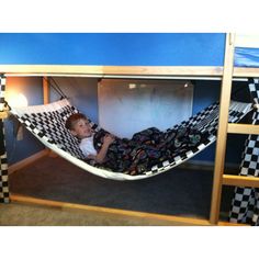 a young boy laying in a hammock bed with checkered sheets on it