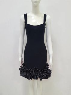 a white mannequin wearing a black dress with ruffles on the bottom