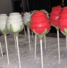 there are many cake pops with green and red frosting on them, all lined up in the same row