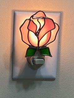 a light that is on the side of a wall with a glass flower in it