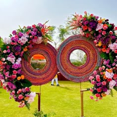 two circular sculptures made out of yarn and flowers in the middle of a grassy field