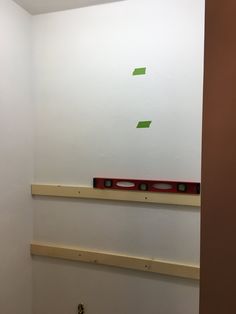 a white wall with some green stickers on it and a red box in the corner