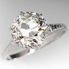 an old mine cut diamond ring on a white background with the center stone surrounded by diamonds