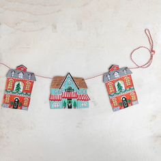 some paper houses are hanging on a line with red twine and string attached to them