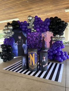 purple and black balloons are on display in front of an arch that has been decorated with photos