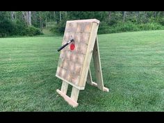 an easel in the middle of a field with a red ball stuck to it