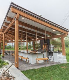 a covered outdoor kitchen area with grill and picnic table