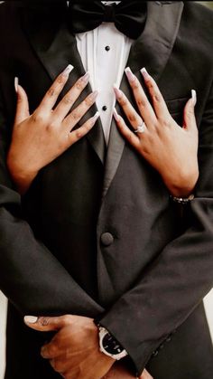 a man in a tuxedo with his hands on his chest and the woman's nails painted white